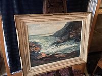 Full front view of the framed oil painting depicting an ocean coast scene with waves and rocks, showing the overall condition and presentation.