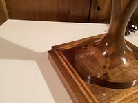 Close-up image showing the marquetry wood base with checkerboard and bordered inlay details on a white background.