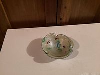 Top view of Murano glass bowl showing rounded triangular shape with embedded green and red decorative flecks and bubble texture inside clear glass.