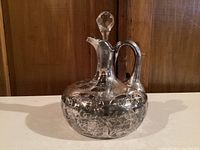 Front view of the Art Deco crystal decanter with silver overlay, showing the floral and geometric silver design and faceted crystal stopper.