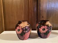 Two Tunstall floral ceramic vases side by side on a white surface with wooden background.