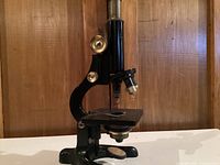 Front-left angled view of the vintage microscope showing the base, stage, and objective lenses.
