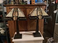 Both lamps side by side on white platform against wooden backdrop