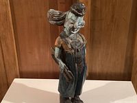 Front view of hand-carved folk art clown figurine showing the face, detailed hands, and clothing.