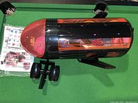 Top view of LOL OMG Remix 4-in-1 Plane toy showing black body with orange translucent side panels and pink nose cone with instruction manual and sticker sheet included.