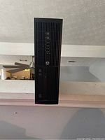 Front view of black HP desktop tower showing front panel with USB ports, audio jacks, power button, and optical drive.