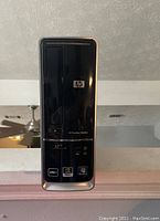 Front view of the HP Pavilion Slimline desktop showing the power button, DVD drive, and all front stickers including AMD, NVIDIA, and Windows 7 Home Premium.