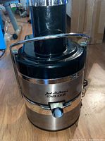 Front view photo of Jack Lalanne Power Juicer showing stainless steel and black plastic body with locking arm and spout.