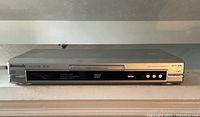 Front view of Panasonic DVD Player Model DVD-S37 showing disc tray, display panel, and control buttons on a silver rectangular body.