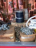 Chains stored in wooden boxes, synthetic wire spools stacked on top of a cardboard box with labeling