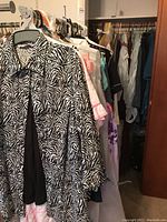 Full view of clothing rack showing multiple women's clothing items including zebra print jacket in front.