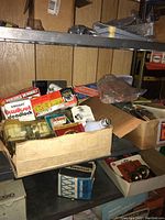 General view of shelving with boxes containing locks, deadbolts, light bulbs, and hardware items
