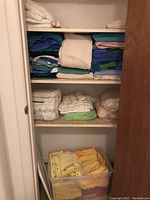 Closet shelf with assorted folded linens including towels, sheets and table linens