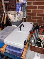 Photo showing bucket with assorted extension cords and surge protectors alongside white Duracell lock rekeying kit case and some hauling shackles and straps.