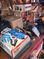 Various boxes and power tools including Weller soldering gun box, soldering wire spools, 5 inch bench grinder box, power stripper box, and assorted tools on table