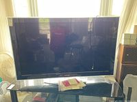 Front view of Samsung 55 inch LED TV with glass stand and paperwork on top.