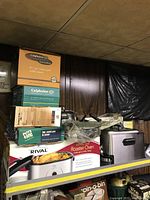 Stacked cookware boxes and small appliances on shelf
