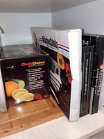 Boxed Chef's Choice Diamond Hone Sharpener and KüchenStolz knife set along with other boxed cutlery and knife sharpener items on shelf.