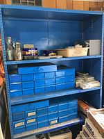 Blue metal shelving unit with multiple blue storage bins containing various small hardware items
