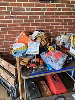 Overview of assorted hand tools, tool belt, gloves, and shop towels on table with Black & Decker workbench below.