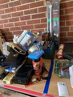 Photo showing assorted hand tools, torque wrench in packaging, staplers, and small tool boxes on table.