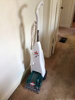 Front view of Bissell Quicksteamer carpet cleaner showing white body, cord wrapped around handle, and teal cleaning head with logo and model name.