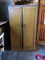 Front view of the wood cabinet showing double doors, wood handles, and overall condition with scratches and wear.