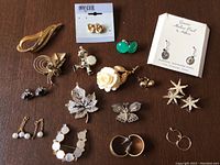 Full lot view showing all pins, brooches, and earrings arranged on a table including some in packaging.