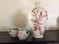 Three hand-painted Nippon pieces: large decorative vase with brown and purple thistle leaves and two smaller cream/sugar porcelain pieces with pink floral decoration
