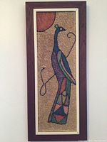 Framed art depicting stylized bird with colorful abstract mosaic pattern on textured background.