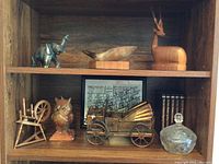 Wooden shelf display showing all items including animal figurines, metal car, crystal dish, ceramic owl, wooden chair, framed print, and books