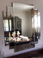 Three-panel rectangular mirror mounted on wall with visible bevels and reflections of room furnishings