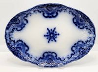 Top-down view of oval flow blue platter showing overall blue fading design, embossed decorations and central floral star.