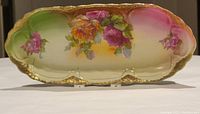 Full view of the antique celery dish showing shape, colors, and floral painting with gold trim.