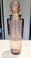 Full view of the blown glass bottle showing its height and smooth tinted surface