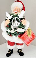 Front view of Department 56 Possible Dreams Peace Wreath Santa figurine holding wreath with peace symbol and doves.