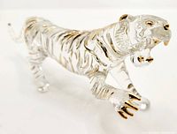 Angled close-up view of clear glass tiger figurine showing gold accents on face, claws, and stripes.