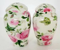 Pair of pink rose floral full-size salt and pepper shakers, hand-painted, showing side views with holes on top and rose pattern on white ceramic.