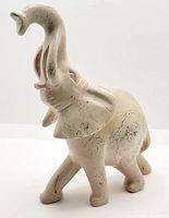 Front and side view of hand carved soap stone elephant showing the raised trunk, ear details, and natural marbled stone pattern.