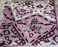Close-up of the tablecloth fabric showing elephant and floral motifs in mauve and purple shades.