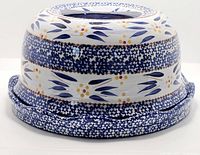 Hand painted ceramic dish with lid turned upside down, showing floral and leaf blue and white pattern with yellow and orange highlights.