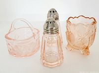 View of group of four items showing pink Depression glass salt and pepper shakers, toothpick holder, and small basket.