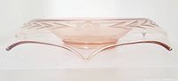 Side view of the pink glass bowl showing the rolled collar with etched floral and leaf design and pointed corners.