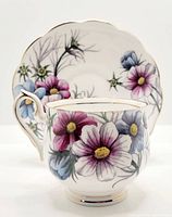 Cup and saucer front view showing cosmos flower hand painting and gold trim