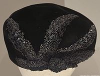 Top view of black velvet hat displaying extensive bead patterns in radiating and clustered designs.