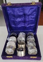 Set of 12 silver plate napkin rings in original purple velvet box with satin lining.