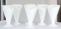 Set of six white waffle cone style ceramic ice cream cups arranged in a line showing their shape and texture.