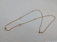 Full view of 22-inch chain necklace laid flat displaying six pearl-like beads.