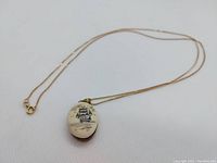 Full view of the gold chain with the ceramic and wood tall ship pendant on white background.