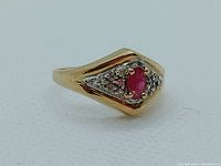 Front view of ring showing diamond-shaped head with ruby center and clear stones